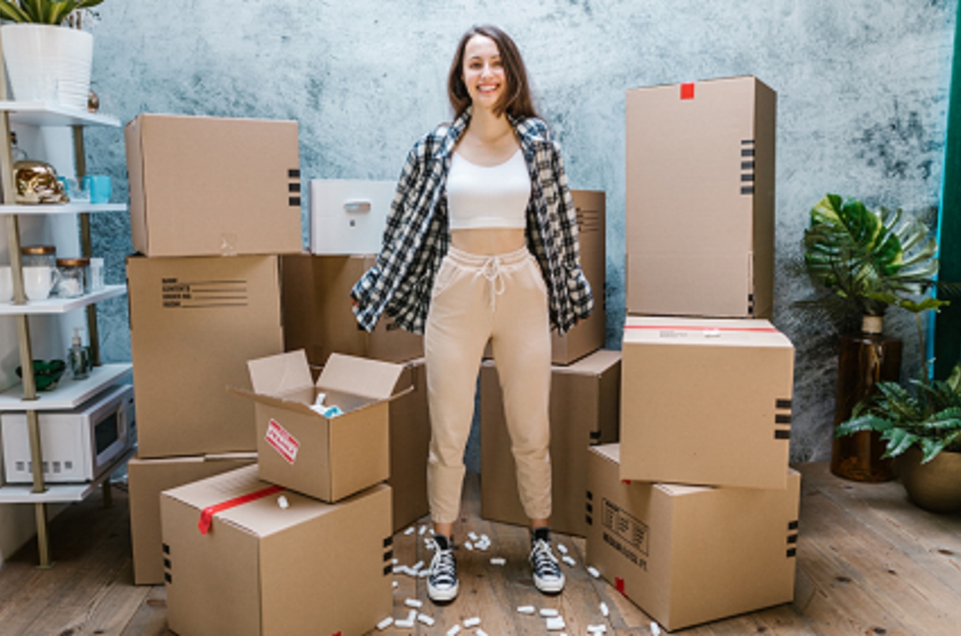 Smiling woman standing among moving boxes while preparing to relocate home, Removalist Service