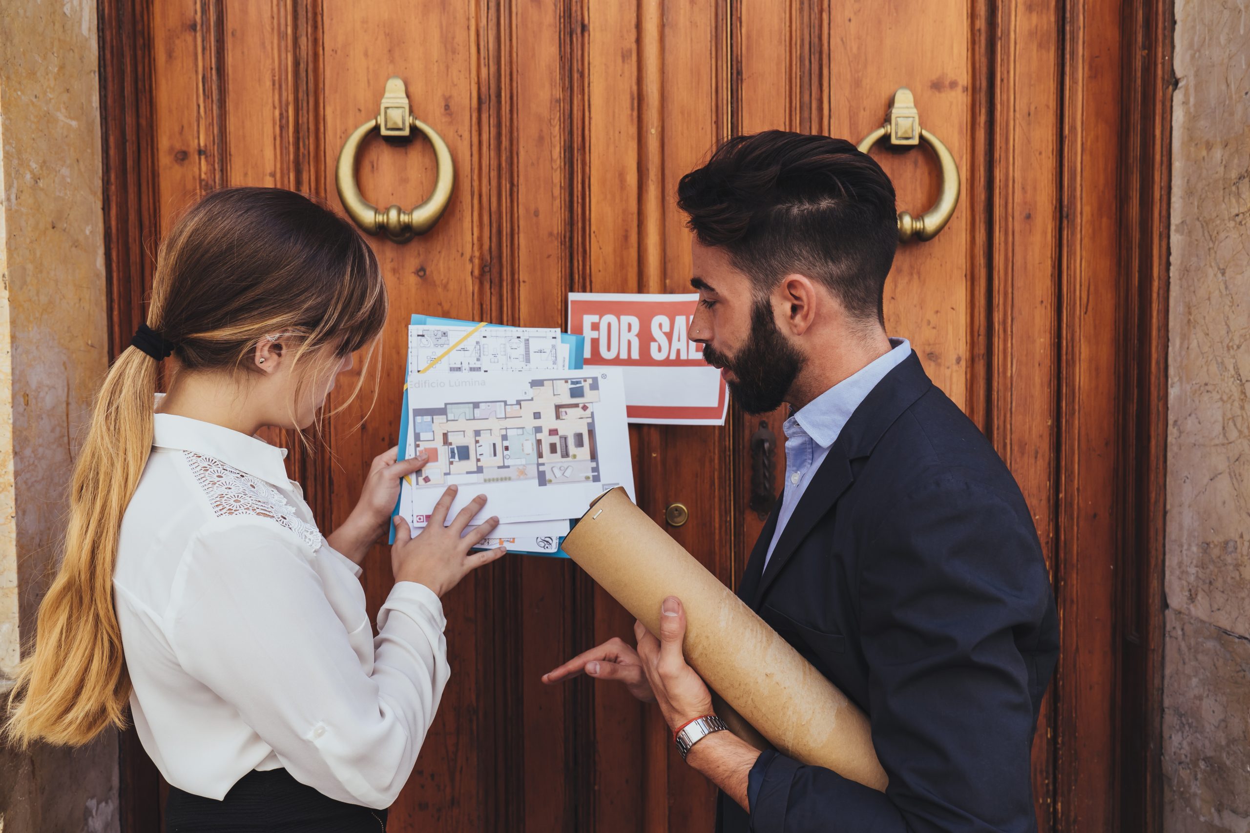 How to stage a house for sale in Melbourne — real estate agent and buyer reviewing property floor plan outside a for sale home